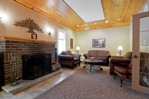 A photo of an interior planning room at Pilon Family Funeral Home showcasing a fireplace, comfortable couch, and seating.